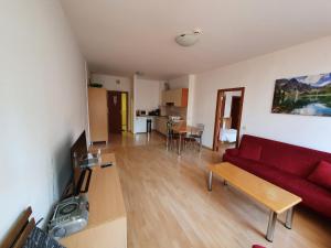 a living room with a red couch and a table at Flora Apartments TMF in Borovets