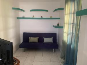 un sofá azul en una sala de estar con estanterías verdes en Villa Karata Appartement T3 avec Spa et vue sur mer BAILLIF Basse-Terre, en Baillif