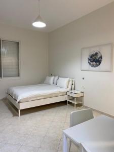 a white bedroom with a bed and a table at Hotel Rehovot in Rechovot