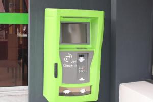 une machine à atm vert néon dans un bâtiment dans l'établissement Logis Hôtel- Restaurant La Renaissance, à Baccarat