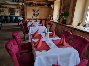 une rangée de tables dans un restaurant avec des serviettes rouges dans l'établissement Hotel und Pension Al Dente, à Nünchritz
