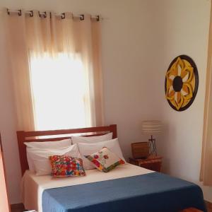 um quarto com uma cama com um cobertor azul e uma janela em Pouso da Ermelinda em Tiradentes