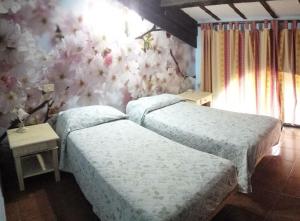 two beds in a room with flowers on the wall at Agriturismo Il Poderino in Tarquinia