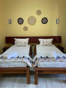 two beds sitting next to each other in a room at Havana Hôtel in Morondava