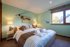 a bedroom with a large bed with towels on it at Tanglewood Lodge in Lossiemouth