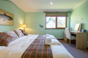 a bedroom with a bed and a desk with a computer at Tanglewood Lodge in Lossiemouth