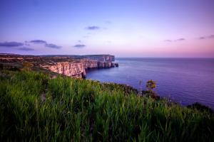 a view of the ocean from a cliff at Fiftyfour West Boutique Living in Għarb