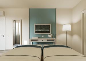 a bedroom with two beds and a tv on the wall at PFA Hotel Viareggio in Viareggio