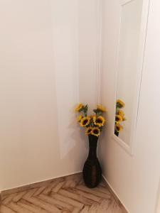 a vase filled with sunflowers in a corner of a room at Bee Studio in Iernut