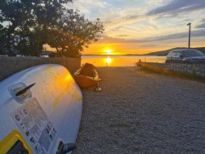 ein Surfbrett am Strand mit Sonnenuntergang in der Unterkunft Apartments Near Sea in Metajna