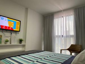 - une chambre avec un lit et une télévision murale dans l'établissement Flat Novíssimo João Pessoa, à João Pessoa