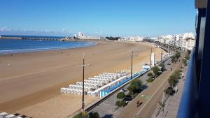 a view of a beach with white umbrellas and the ocean at STUDIO MEUBLE Face mer vue imprenable sur la mer, parking et fibre gratuits in Les Sables-dʼOlonne