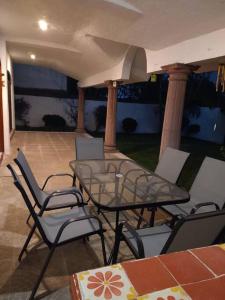 d'une terrasse avec une table et des chaises en verre. dans l'établissement HERMOSA CASA EN CUERNAVACA: JARDÍN DEL LAGO, à Cuernavaca