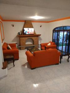 Elle comprend un salon doté d'un mobilier orange et d'une cheminée. dans l'établissement HERMOSA CASA EN CUERNAVACA: JARDÍN DEL LAGO, à Cuernavaca
