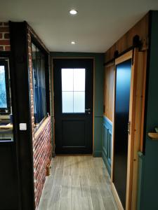 a hallway with a black door and a brick wall at BRUSHWOOD in Longfossé