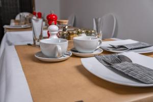 a wooden table with white plates and cups on it at Magnolia House, Rye in Rye