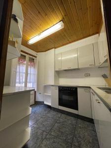 cocina con electrodomésticos blancos y techo de madera en Can Xuneta, en Bagá