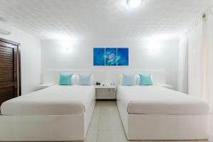 2 letti in una camera con pareti bianche e cuscini blu di Paradise Beach Hotel a West Bay