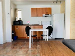 La cuisine est équipée d'une table, de chaises et d'un réfrigérateur blanc. dans l'établissement Attitude Montagne, à Saint-Adolphe-d'Howard