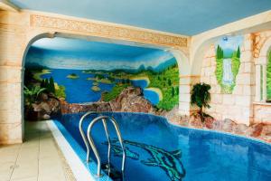 a swimming pool in a resort with a painting on the wall at Perła Karkonoszy SPA in Karpacz