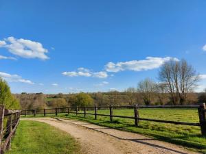 uma estrada de terra num campo ao lado de uma cerca em Relais équestre du Miloir - chambres d'hôtes em Saint-Martin-de-la-Lieue