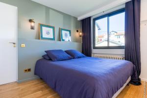 um quarto com uma cama azul e uma janela em VILLA BIBI CHERI Elégante Suite de 35 M2 em Biarritz