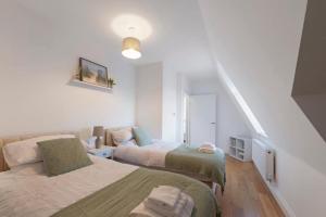 um quarto branco com 2 camas e uma escada em Spacious Two Bed loft Apartment em Birchanger