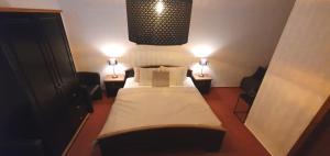 a small bedroom with a bed and two lamps at Stadthotel in Rochlitz