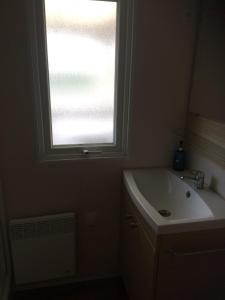 een badkamer met een wastafel en een raam bij 3 Bedroom Holiday Home at Siblu in Pont-Aven