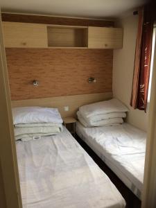 2 bedden in een kleine kamer met witte kussens bij 3 Bedroom Holiday Home at Siblu in Pont-Aven