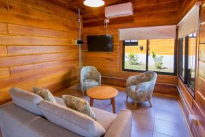 uma sala de estar com um sofá e cadeiras e uma televisão em Monviso - Casas de montaña em Santa Rosa de Calamuchita