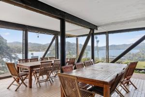 Habitación con mesas, sillas y vistas al agua. en Tipi and Bobs Waterfront Lodge en Tryphena