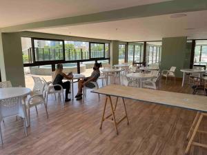 two women sitting at tables in a restaurant at Ilusion flat Ponta Negra in Natal
