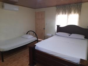 1 dormitorio con 2 camas y ventana en Cabinas Playa Agujas, en Quebrada Ganado