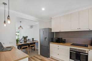 a kitchen with white cabinets and a stainless steel refrigerator at Becca's on Burke in Bright +8 photos