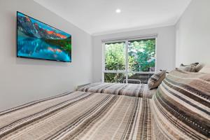 a bedroom with two beds and a tv on the wall at Becca's on Burke in Bright