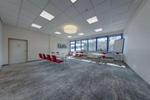 une salle de conférence avec des chaises rouges, une table et un écran dans l'établissement Best Western Hotel Wetzlar, à Wetzlar