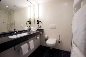 a bathroom with a toilet and a sink and a mirror at Nordsee Hotel City in Bremerhaven
