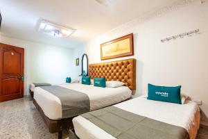 2 letti in camera d'albergo con cuscini blu di Ayenda Orquidea 19 a Valledupar