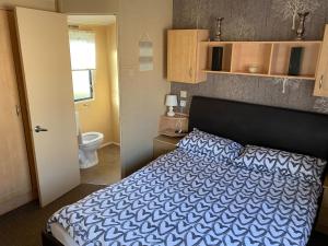 a bedroom with a bed and a bathroom with a toilet at 2 and 3 Bedroom caravans with Hot Tubs at tattershall in Tattershall