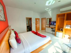 a bedroom with a white bed with a red bow on it at PJ Patong Resortel in Patong Beach