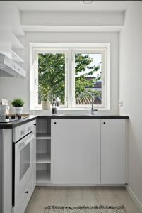 eine weiße Küche mit Spüle und Fenster in der Unterkunft A Place To Stay Stavanger, apartment 2 in Stavanger + 22 Fotos