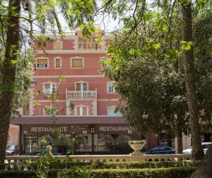 a pink building in front of a street with trees at Hotel Felix in Lorca