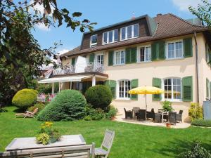 ein Haus mit einem Garten mit Stühlen und einem Sonnenschirm in der Unterkunft Villa Neugarten in Hagnau