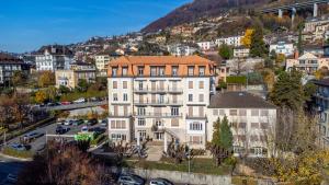 a large white building with an orange roof in a city at Miramonte Single Lake View Room in Montreux