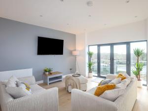 a living room with two white couches and a flat screen tv at Bryn Min Manton Apartment in Caernarfon