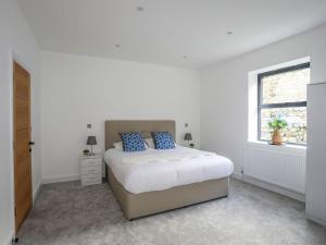 a white bedroom with a bed and a window at Bryn Min Manton Apartment in Caernarfon