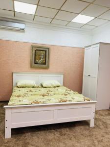 Bett in einem Zimmer mit einem weißen Bettrahmen in der Unterkunft Бульвар Эркиндик74 in Bischkek