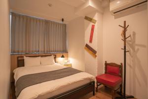 大阪市にあるYeah Room Nambaのベッドと赤い椅子のある寝室