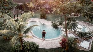 un hombre de pie junto a una piscina en Village Bali en Uluwatu